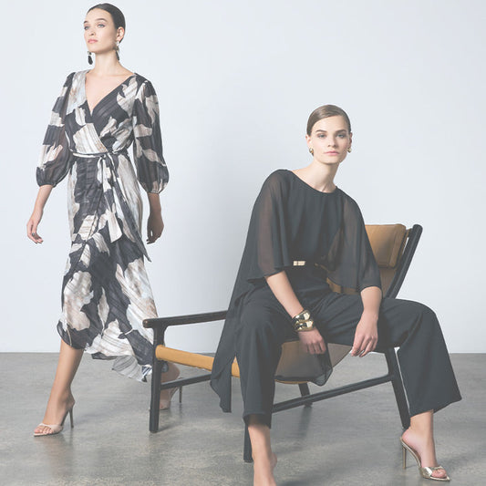 Two Models; left side model wearing printed wrap dress, second model seated in a black jumpsuit