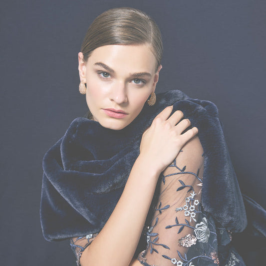 Model in navy fur wrap wearing a navy embroidered gown.